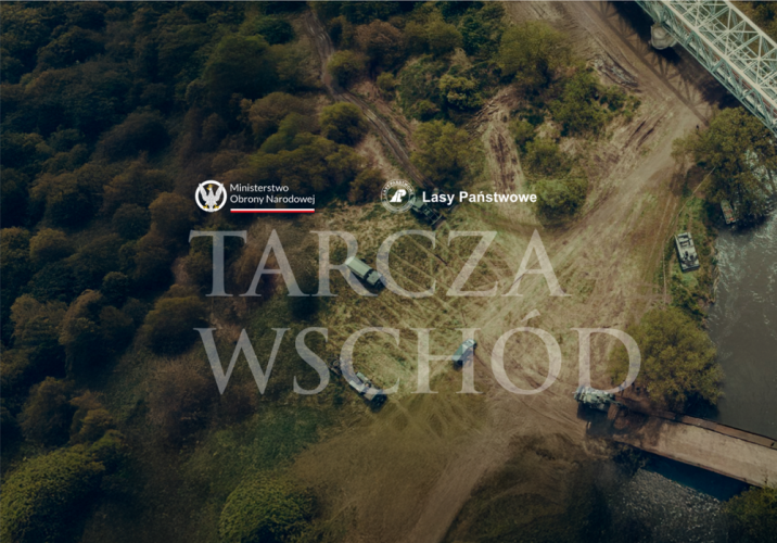 Grafika&#x20;&#x22;Tarcza&#x20;wschód&#x22;&#x20;i&#x20;logotypami&#x20;Ministerstwa&#x20;Obrony&#x20;Narodowej&#x20;i&#x20;Lasów&#x20;Państwowych&#x2e;&#x20;W&#x20;tle&#x20;ujęcie&#x20;z&#x20;drona&#x20;na&#x20;drogę&#x20;przy&#x20;rzece&#x2c;&#x20;fragment&#x20;mostu&#x20;i&#x20;samochody&#x20;wojskowe&#x2e;